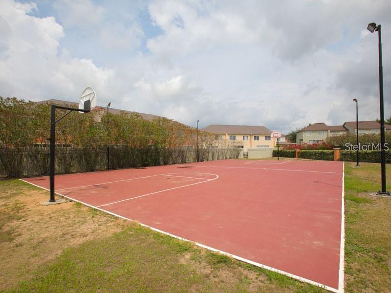 An outdoor basketball court with a red surface, two hoops, and surrounding landscaping — 352 CARIBBEAN DRIVE UNIT Front, DAVENPORT, FL