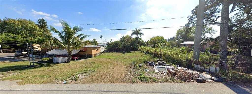 A vacant, grassy lot with scattered debris sits between a house and a palm tree — 205 SE 1ST AVENUE, SOUTH BAY, FL