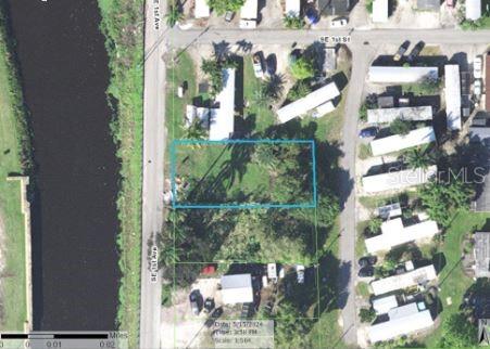 This aerial map shows a rectangular vacant lot highlighted in blue next to a canal — 205 SE 1ST AVENUE, SOUTH BAY, FL