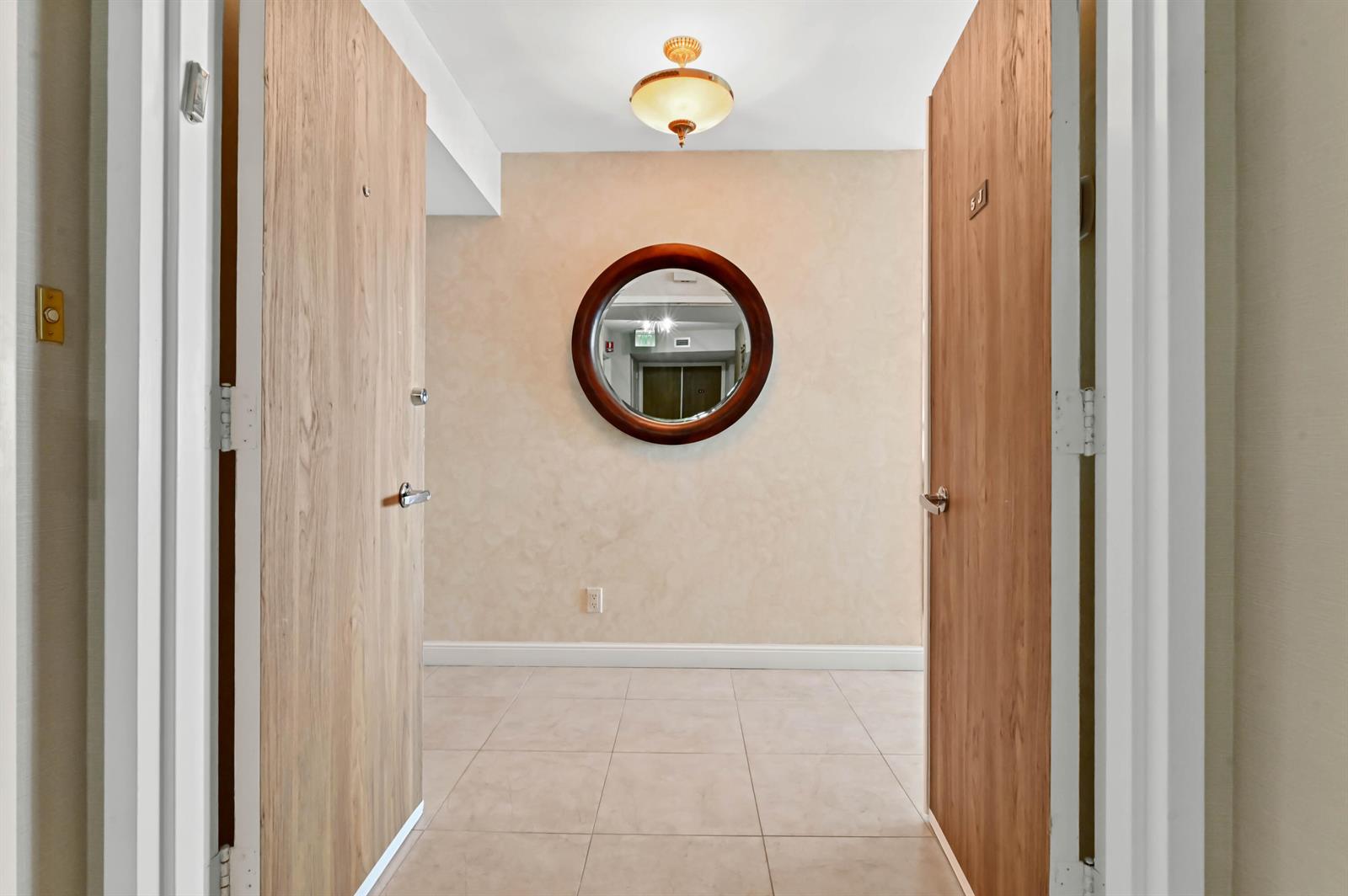 A tiled entryway features two wooden doors, a circular wall mirror, and a ceiling light — 2800 S Ocean Boulevard Apt j, Boca Raton FL 33432, BOCA RATON, FL