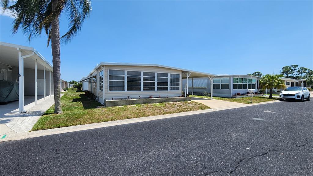 A single-story manufactured home with a light-colored exterior, large windows, and a brick planter — 3226 SWEET BAY TERRACE, SARASOTA, FL