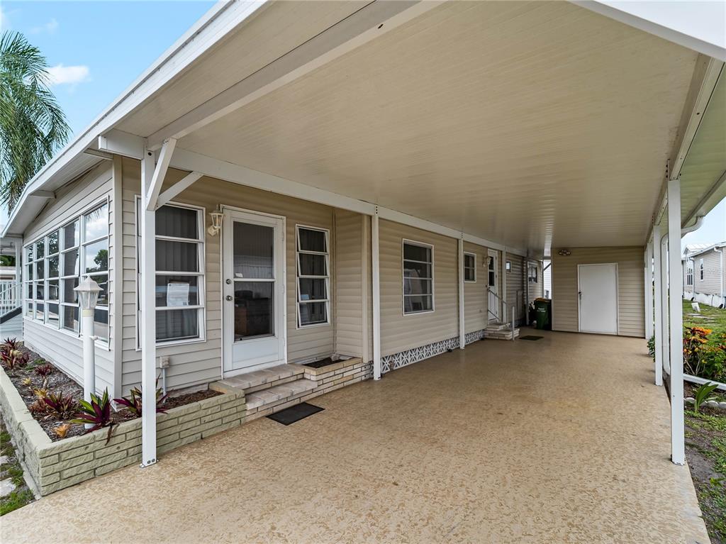 A beige mobile home features a covered carport, a concrete driveway, and a small garden bed — 3226 SWEET BAY TERRACE, SARASOTA, FL
