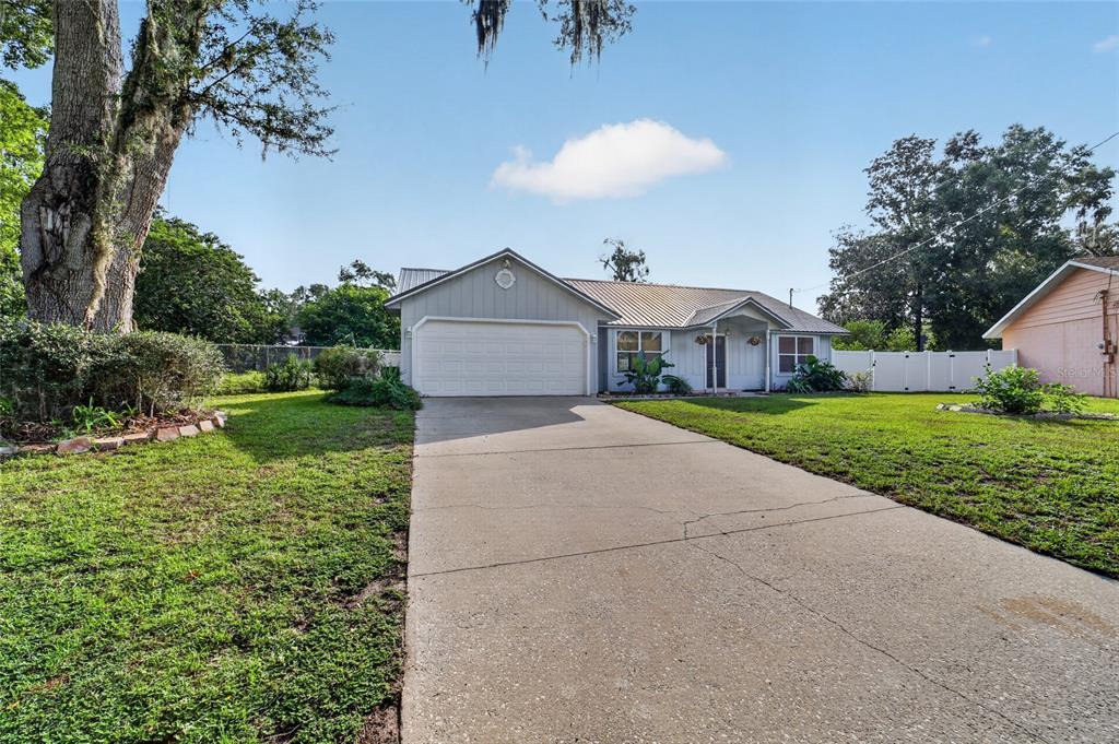A single-story house with a metal roof, two-car garage, and a concrete driveway — 4861 SE 31ST TERRACE, OCALA, FL