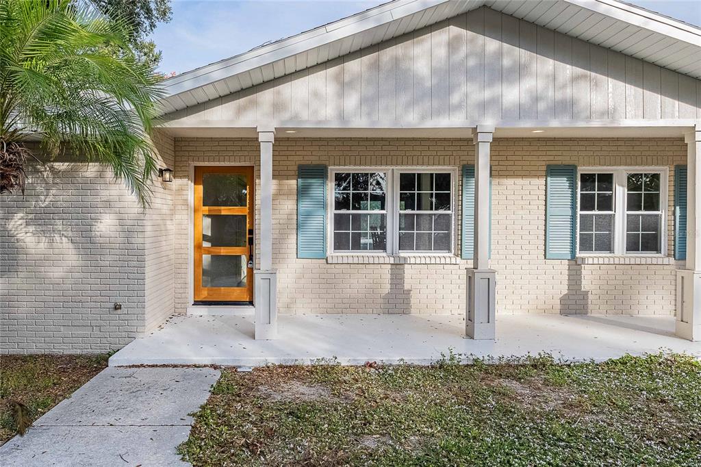 A single-story house with a brick facade, a covered porch, and a wooden front door — 6212 WOODSFIELD WAY, LAKELAND, FL