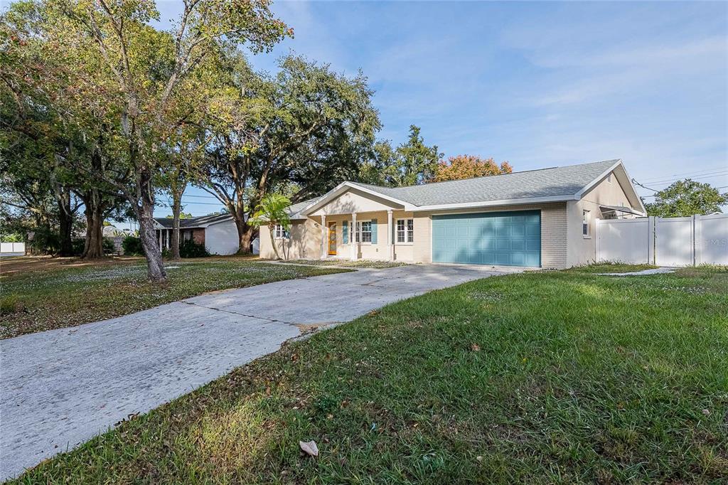 A single-story house with a light-colored brick exterior, a blue garage door, and a driveway — 6212 WOODSFIELD WAY, LAKELAND, FL