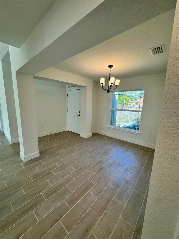 An interior view of a dining area with wood-look tile flooring and a chandelier — 7933 TROPICAIRE BLVD., NORTH PORT, FL
