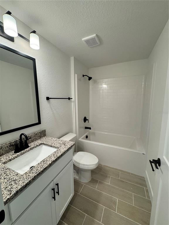 A bathroom features a granite vanity, white cabinets, a subway-tiled tub, and tile flooring — 7933 TROPICAIRE BLVD., NORTH PORT, FL