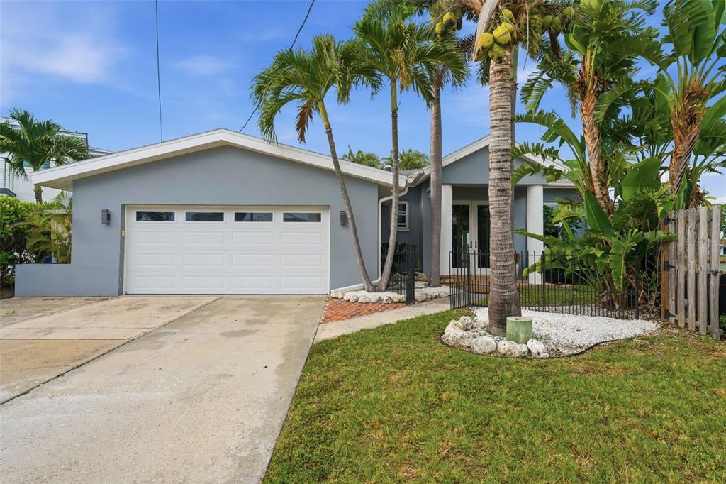 A gray single-story house with a white garage door, palm trees, and a front lawn — 16115 4TH STREET E, REDINGTON BEACH, FL