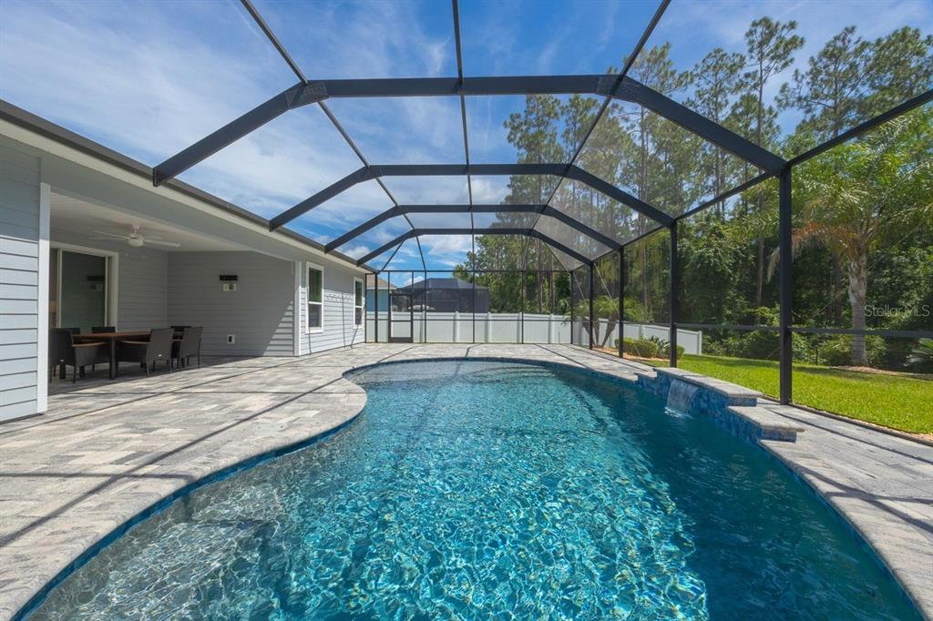 A screened-in patio features a swimming pool with a water feature and paver decking — 213 OLETA WAY, ST AUGUSTINE, FL
