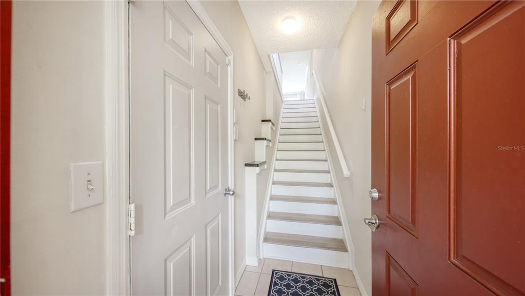 An entryway features a red front door, a white door, and stairs leading upward — 5551 BENTGRASS DRIVE UNIT 11-117, SARASOTA, FL