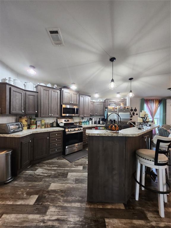 A kitchen features dark wood cabinets, stainless steel appliances, and a granite-topped island with stools — 152 KELLY LANE, HAWTHORNE, FL