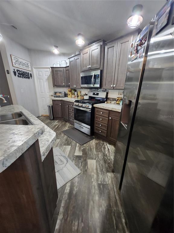 A kitchen features dark wood cabinets, stainless steel appliances, and light-colored patterned countertops — 152 KELLY LANE, HAWTHORNE, FL