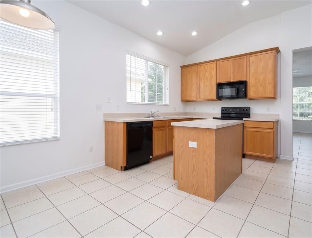A kitchen with light wood cabinets, black appliances, a central island, and tiled flooring — 13424 HOPKINTON CT, WINDERMERE, FL