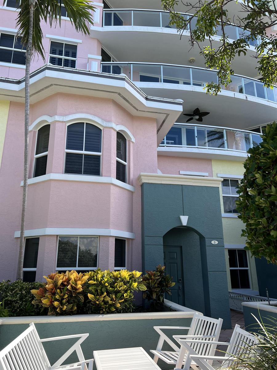 A multi-story building with pink and teal stucco walls features balconies and a patio area — 2051 SE 3rd Street, Deerfield Beach FL 33441, DEERFIELD BEACH, FL