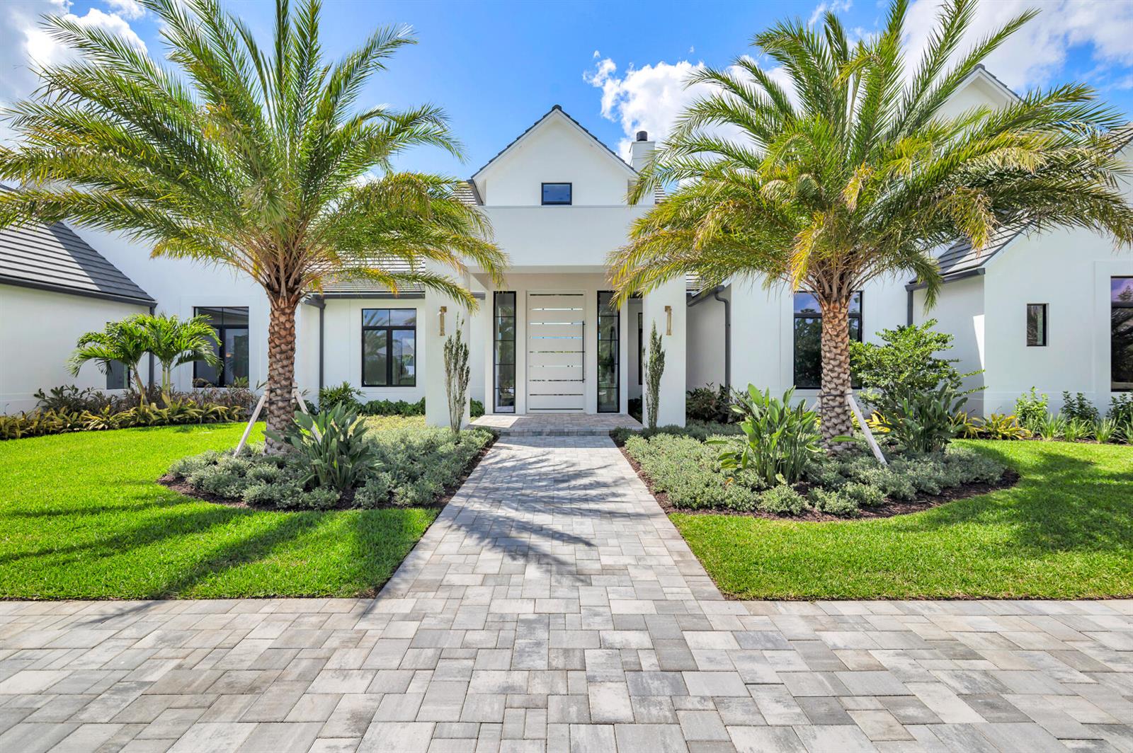 A white modern house with a paved walkway, palm trees, and green landscaping — 2015 Lockheed Terrace, Wellington FL 33414, WELLINGTON, FL