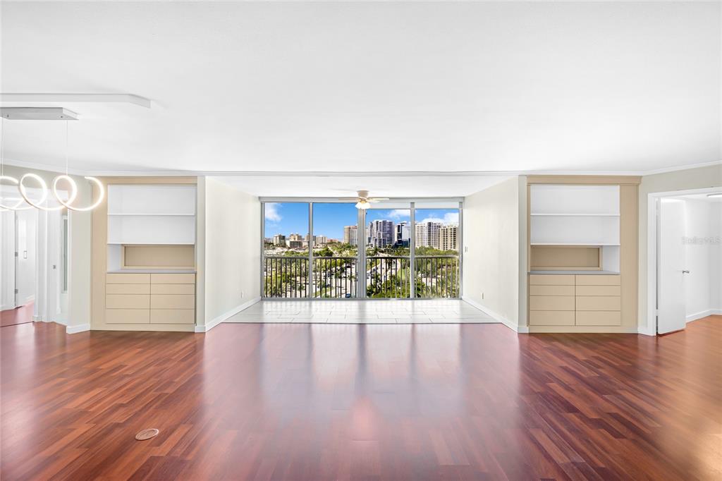 A spacious living room features hardwood floors, built-in cabinetry, and a large window with city views — 435 S GULFSTREAM AVENUE UNIT 1004, SARASOTA, FL