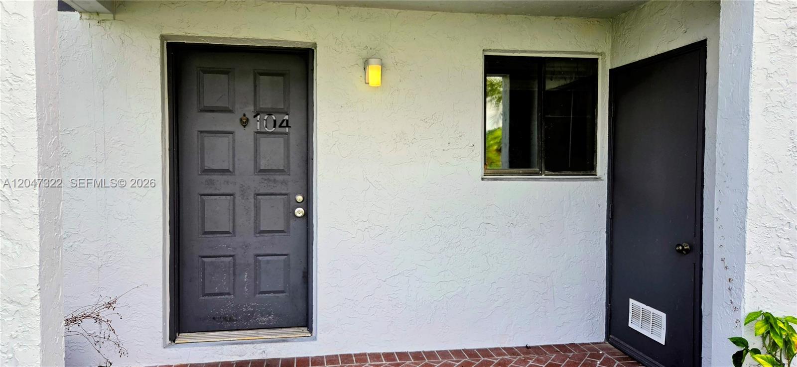 An exterior view shows a dark front door numbered 104, a window, and a utility door — 153 Lakeview Dr # 104, Weston FL 33326, WESTON, FL