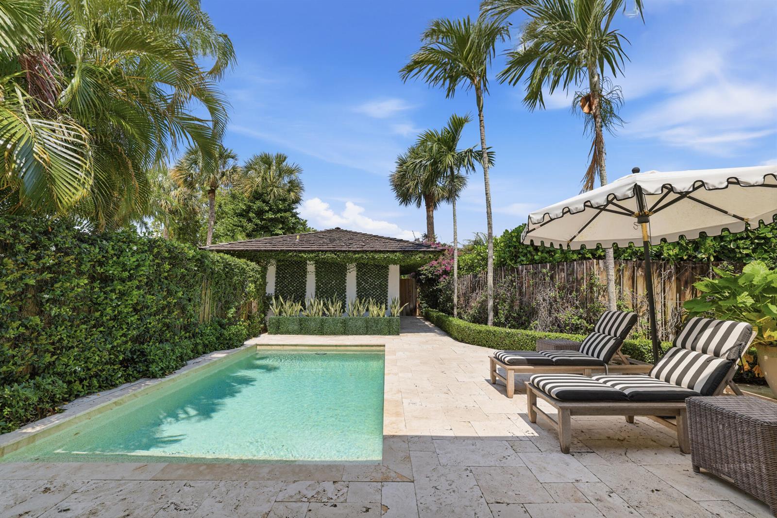 A rectangular swimming pool sits on a stone patio with two lounge chairs and palms — 11760 Marblestone Court, Wellington FL 33414, WELLINGTON, FL