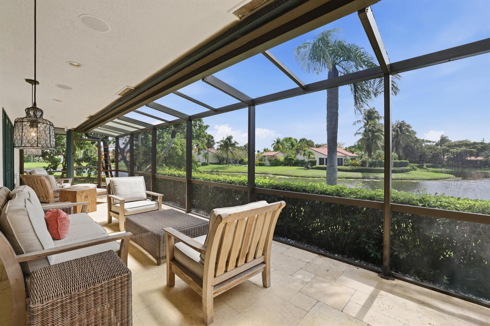 A screened-in patio features outdoor furniture, stone flooring, and a view of a pond — 11760 Marblestone Court, Wellington FL 33414, WELLINGTON, FL