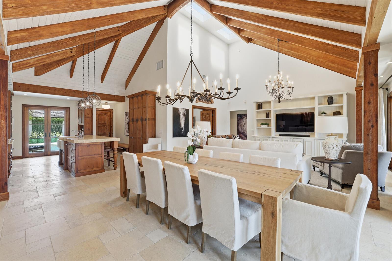 A dining area and kitchen feature vaulted wood-beamed ceilings, stone floors, and white upholstered chairs — 11760 Marblestone Court, Wellington FL 33414, WELLINGTON, FL