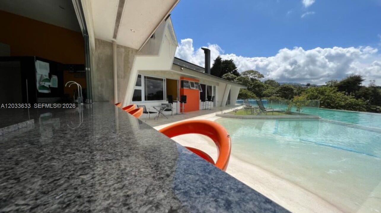An outdoor bar with a granite countertop overlooks a swimming pool and a modern house — Calle Las marias Calle Las marias, FL, FL