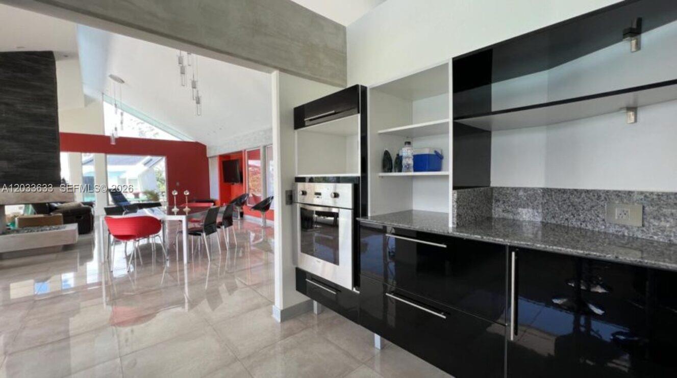 A modern kitchen features black glossy cabinets, granite countertops, and a built-in stainless steel oven — Calle Las marias Calle Las marias, FL, FL