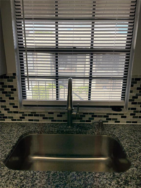 A stainless steel kitchen sink with a gooseneck faucet sits before a window with blinds — 4015 ASHFORD GREEN PLACE UNIT D202, TAMPA, FL