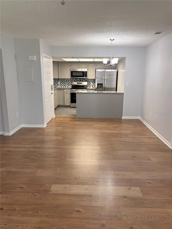 A view of an open-concept kitchen with stainless steel appliances and wood-look flooring — 4015 ASHFORD GREEN PLACE UNIT D202, TAMPA, FL
