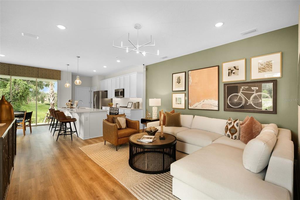 An open-concept living room features a white sectional, leather armchair, and an olive green wall — 693 FLORIDA ELM COURT, DELAND, FL