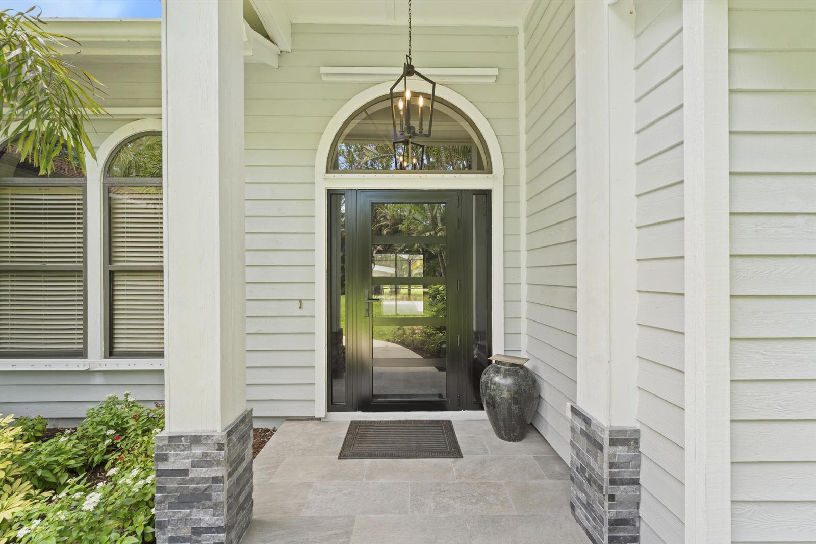 A front porch features a black glass door, stone-accented columns, and a hanging lantern — 15833 118th Trail N, Jupiter FL 33478, JUPITER, FL