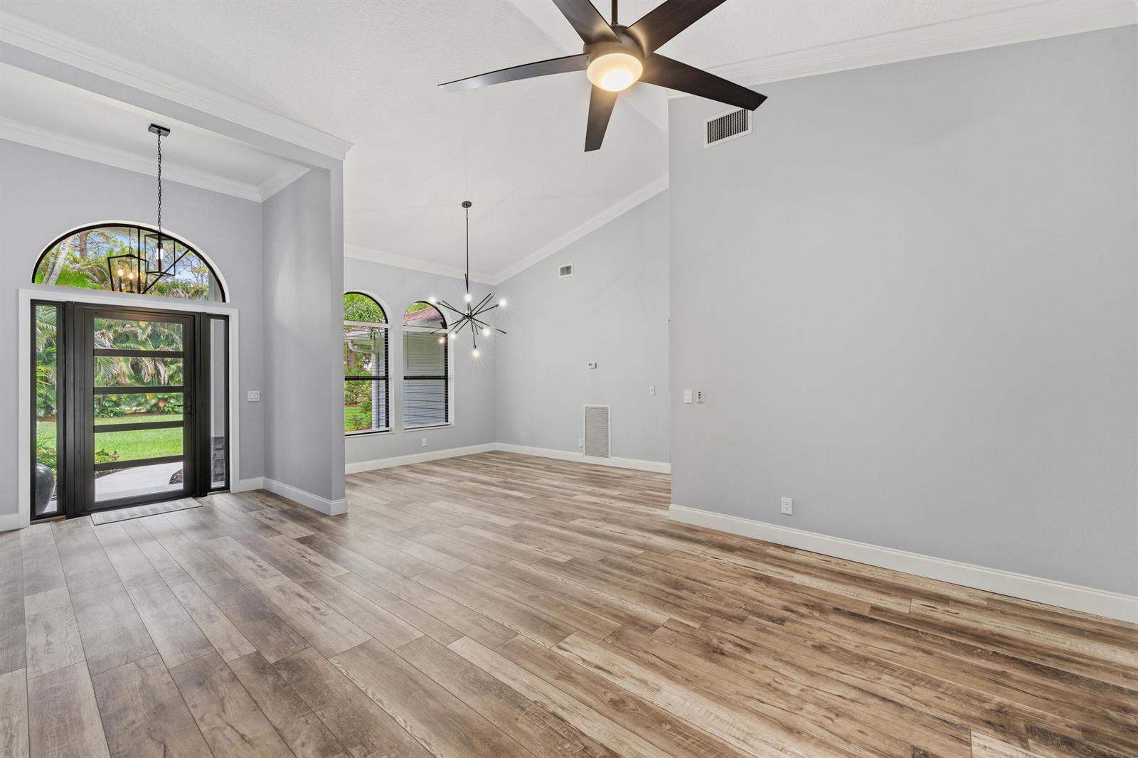 An open living area features light gray walls, wood-look flooring, arched windows, and a ceiling fan — 15833 118th Trail N, Jupiter FL 33478, JUPITER, FL