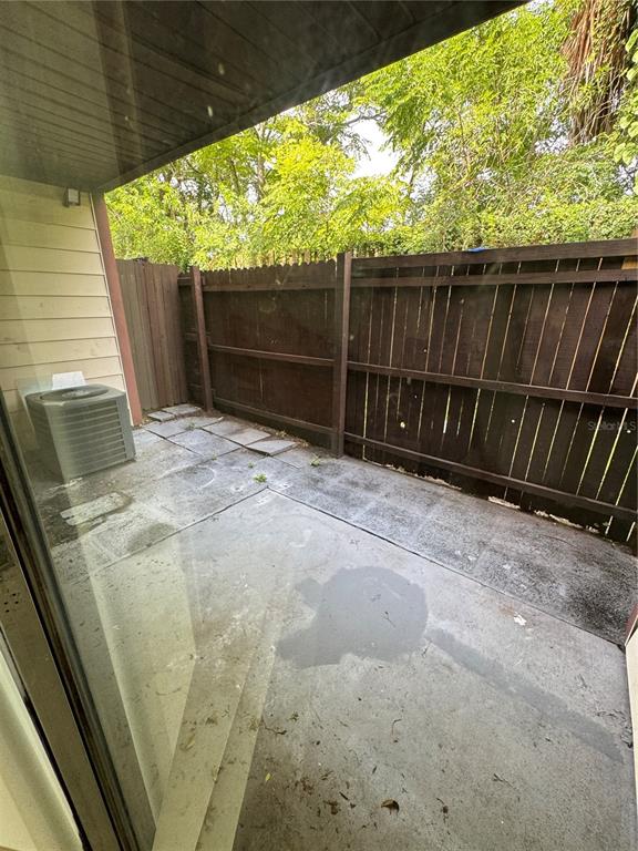 A concrete patio features a wooden privacy fence and an outdoor air conditioning unit — 3976 CRAYRICH CIRCLE UNIT C1, ORLANDO, FL