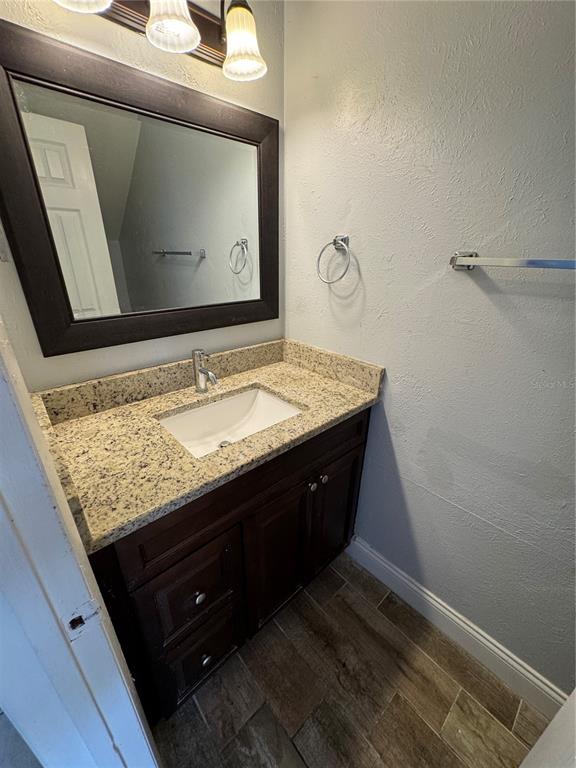 A bathroom features a dark wood vanity with a granite countertop and a framed mirror — 3976 CRAYRICH CIRCLE UNIT C1, ORLANDO, FL