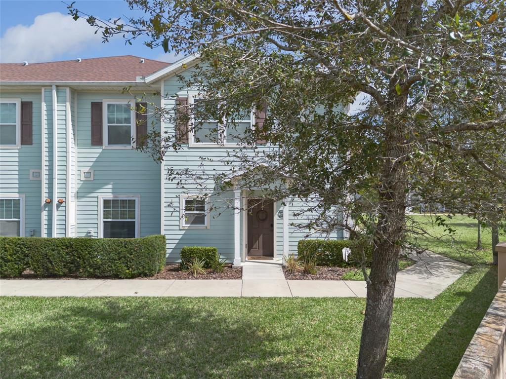 A two-story light blue townhouse with brown shutters and a front door under a portico — 3240 CUPID PLACE, KISSIMMEE, FL