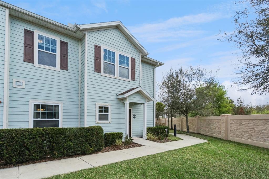 A two-story light blue townhouse with brown shutters and a concrete walkway — 3240 CUPID PLACE, KISSIMMEE, FL