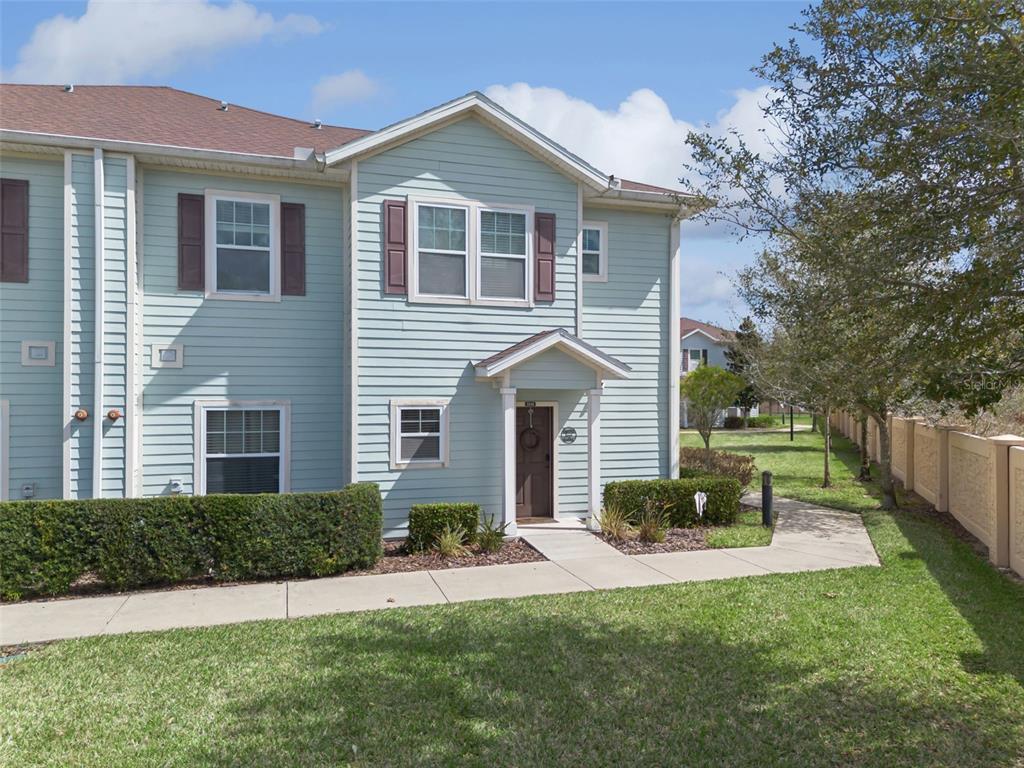 A two-story light blue townhouse with brown shutters and a small covered entryway — 3240 CUPID PLACE, KISSIMMEE, FL