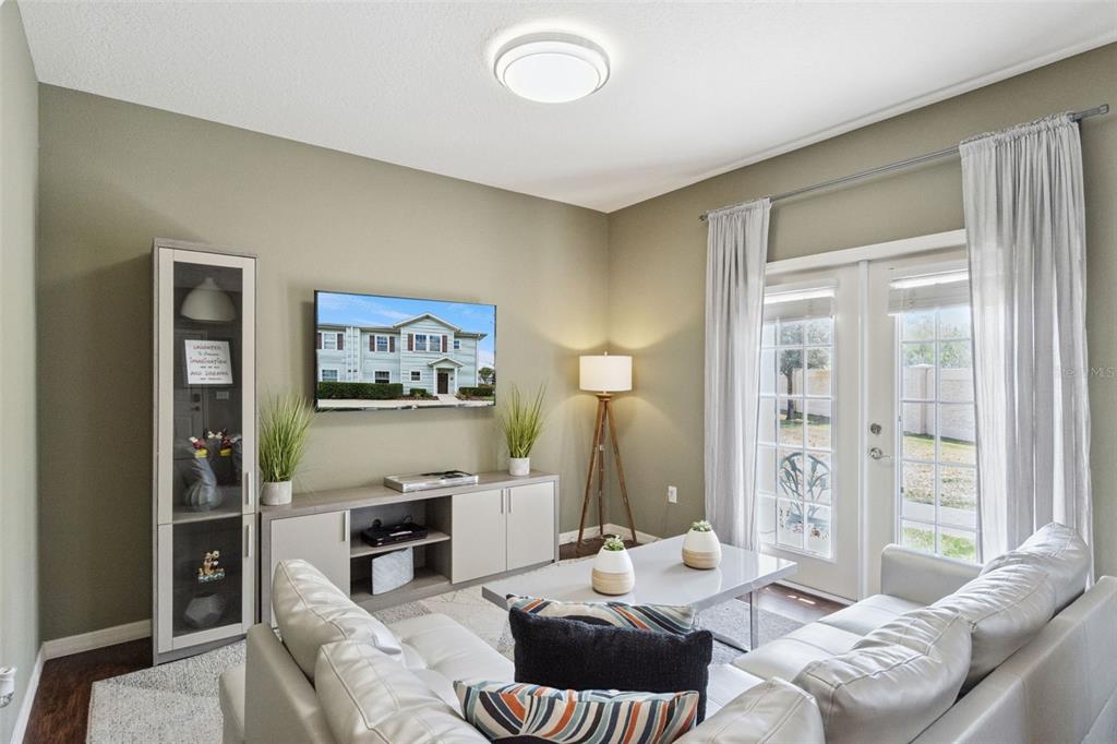 A living room features a wall-mounted television, a light-colored sofa, and glass patio doors — 3240 CUPID PLACE, KISSIMMEE, FL