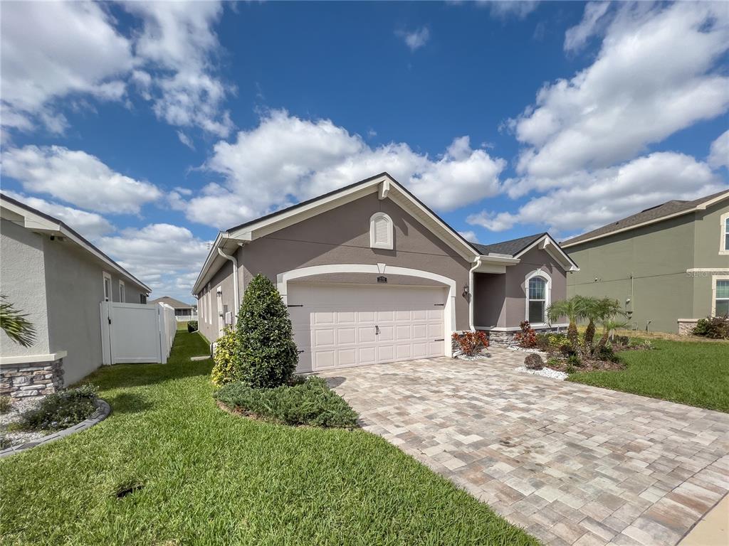 A single-story house with a beige garage, stone accents, and a paved driveway — 13102 SATIN LILY DRIVE, RIVERVIEW, FL