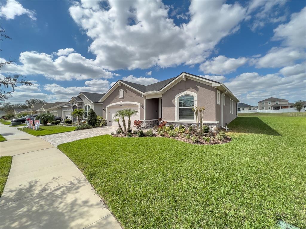 A single-story suburban house with a paved driveway, stone accents, and a manicured lawn — 13102 SATIN LILY DRIVE, RIVERVIEW, FL