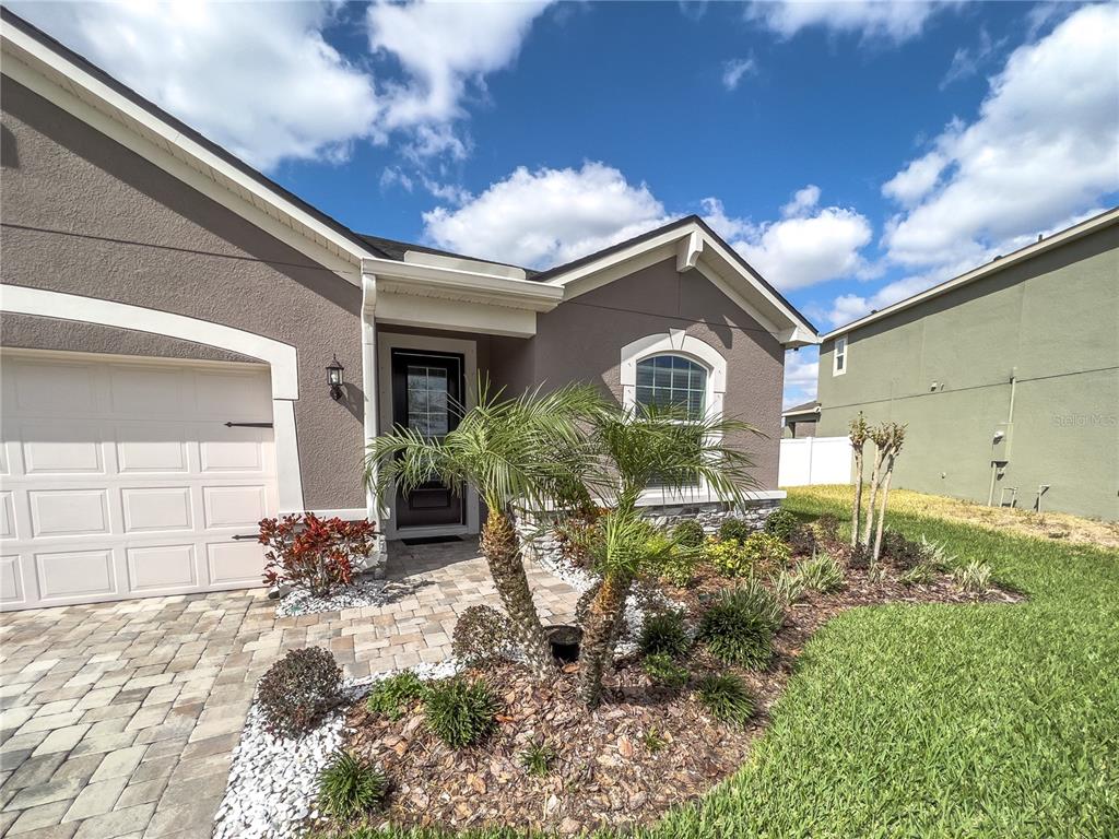 The exterior of a taupe house features a paved driveway, a garage, and a palm tree — 13102 SATIN LILY DRIVE, RIVERVIEW, FL