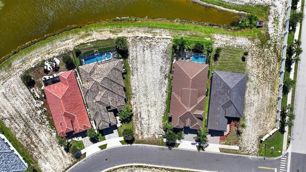 An aerial view shows four residential lots, two with houses and two vacant, near a lake — 7 RIO VISTA DRIVE, PALM COAST, FL