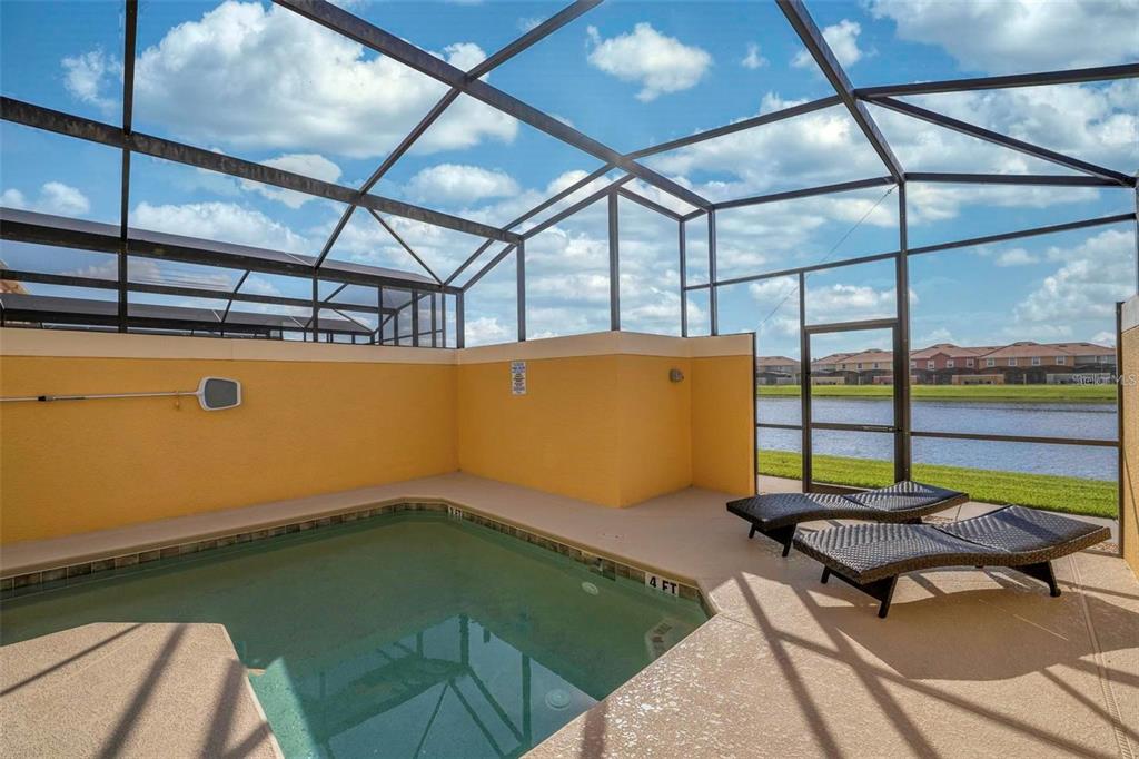 A screened-in patio features a small swimming pool, two lounge chairs, and a lake view — 8859 CANDY PALM ROAD, KISSIMMEE, FL