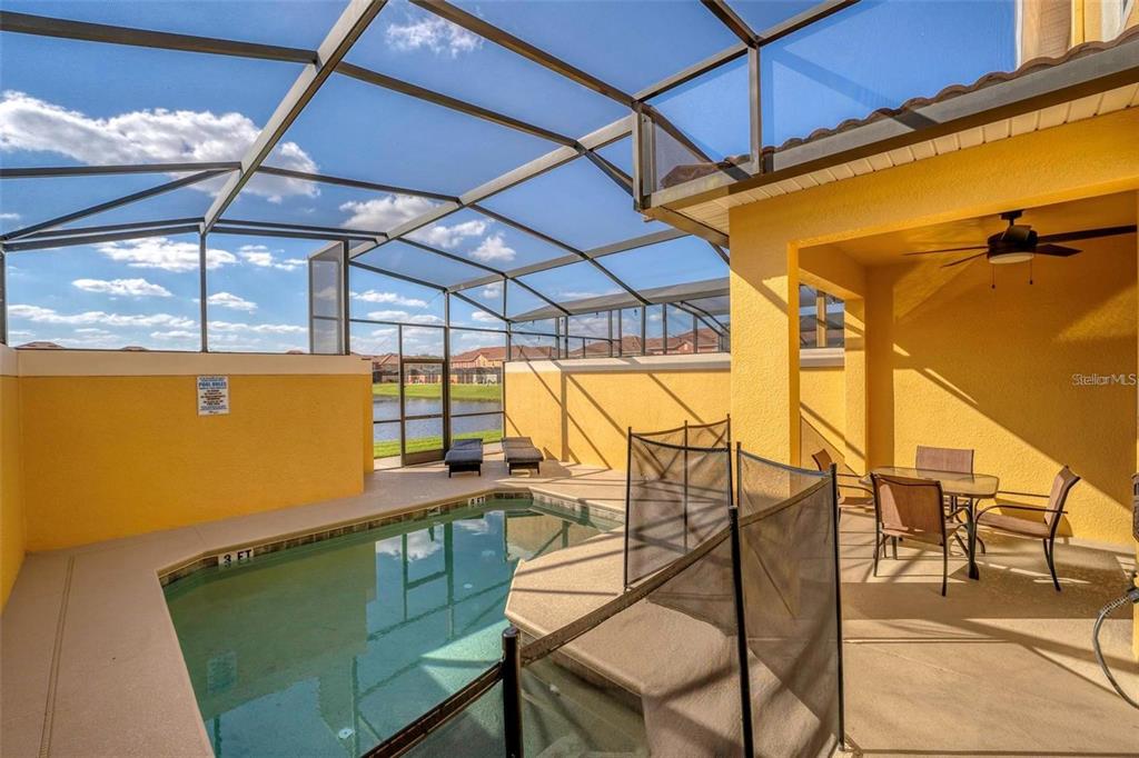 A screened-in patio features a swimming pool, outdoor dining furniture, and a lake view — 8859 CANDY PALM ROAD, KISSIMMEE, FL