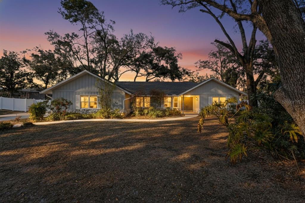 A single-story gray house with a stone foundation sits on a lawn at sunset — 1406 BIG OAK COURT, BRANDON, FL