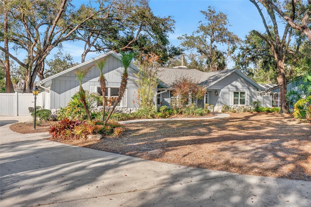 A single-story gray house with vertical siding sits behind a concrete driveway and lawn — 1406 BIG OAK COURT, BRANDON, FL