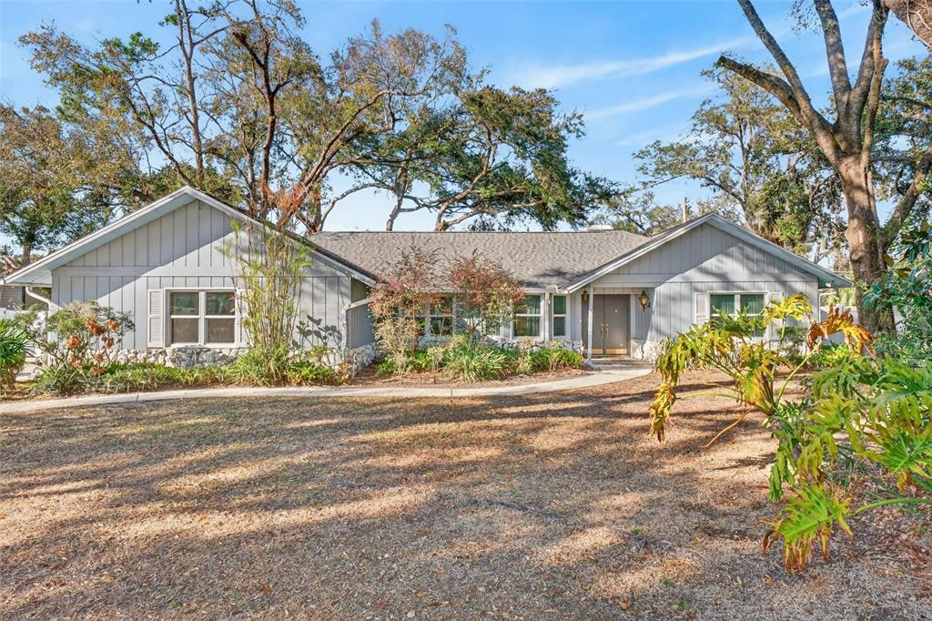 A single-story gray house with vertical siding and a stone base sits behind a lawn — 1406 BIG OAK COURT, BRANDON, FL