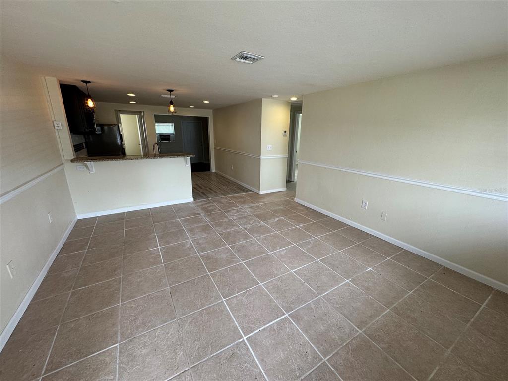 An open-concept living and dining area features tile flooring, chair rail molding, and a kitchen — 2111 FORKED CREEK DRIVE, ENGLEWOOD, FL