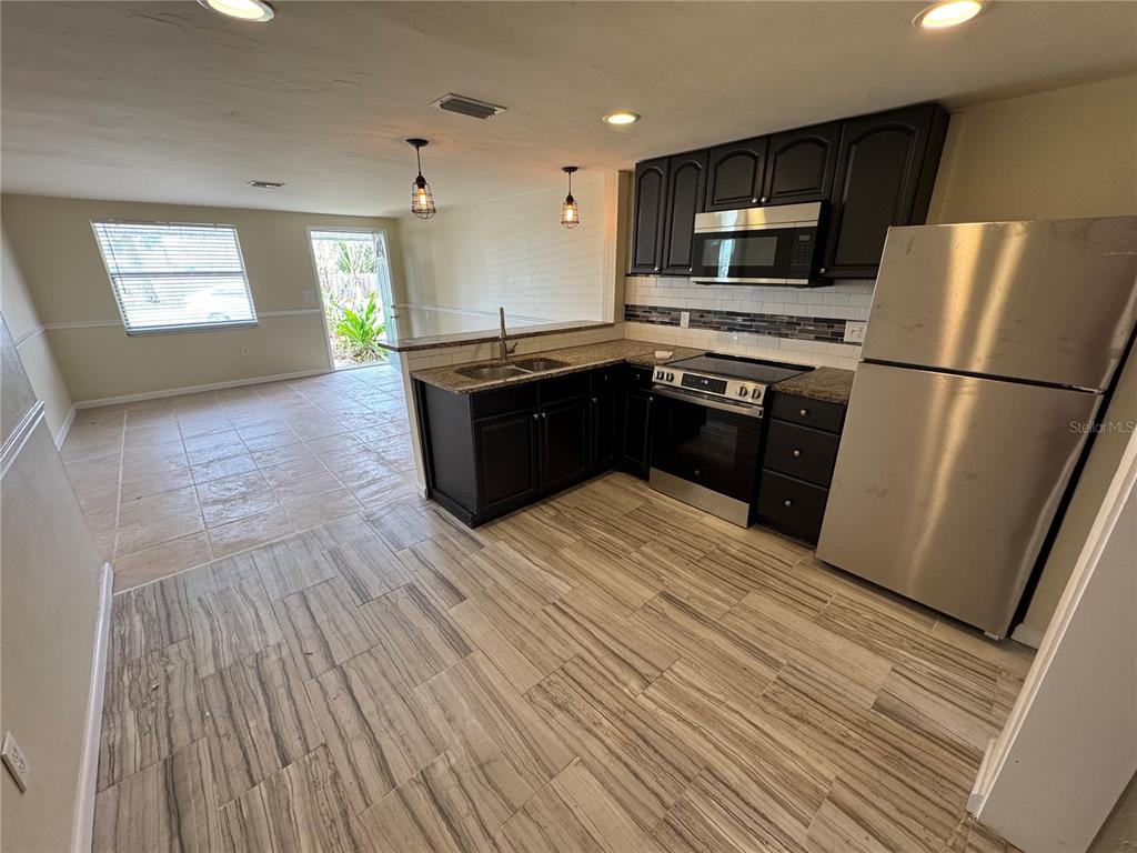 A kitchen with dark cabinets, stainless steel appliances, and wood-look tile flooring — 2111 FORKED CREEK DRIVE, ENGLEWOOD, FL