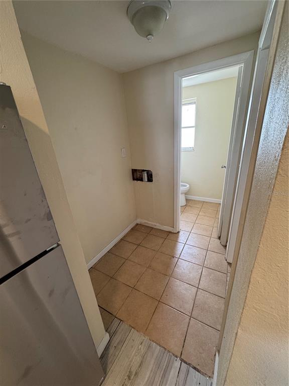 A small laundry area with tiled floors leads into a bathroom with a toilet — 2111 FORKED CREEK DRIVE, ENGLEWOOD, FL