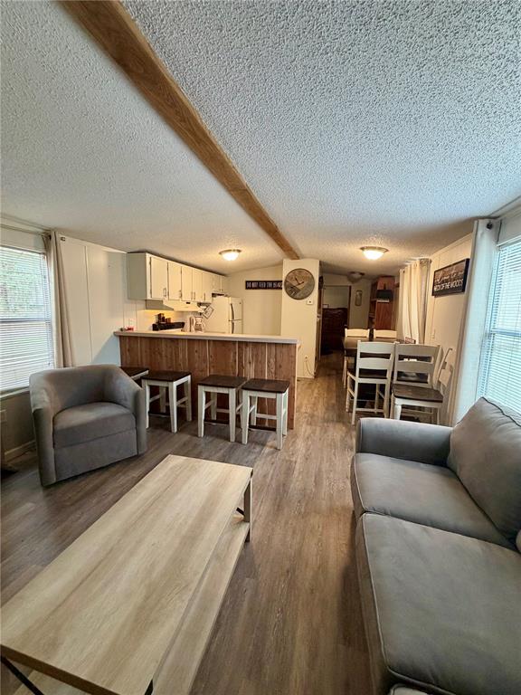 An open-concept living room and kitchen featuring wood-look flooring, a breakfast bar, and neutral furniture — 20445 NE 144TH LANE, FORT MC COY, FL